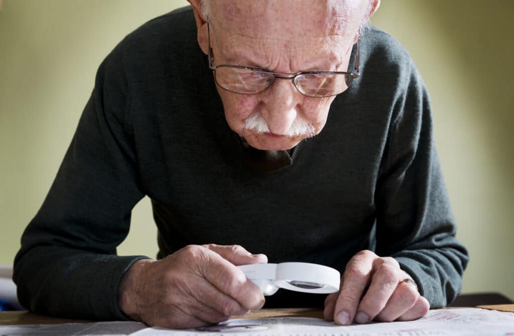 Man with early signs of age-related macular degeneration (AMD) struggles to see fine details in the newspaper in Culpeper