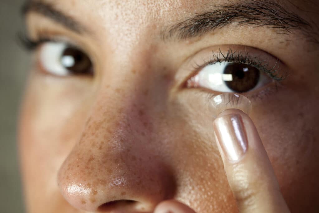 Close-up of a person inserting a contact lens, illustrating specialty contact lens wear.